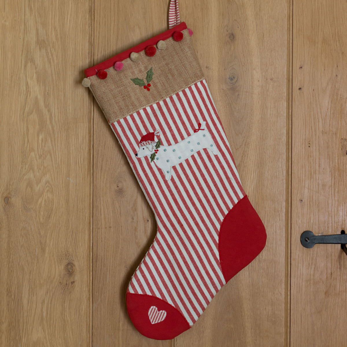 Christmas dog stocking in red ticking hanging on a plank door