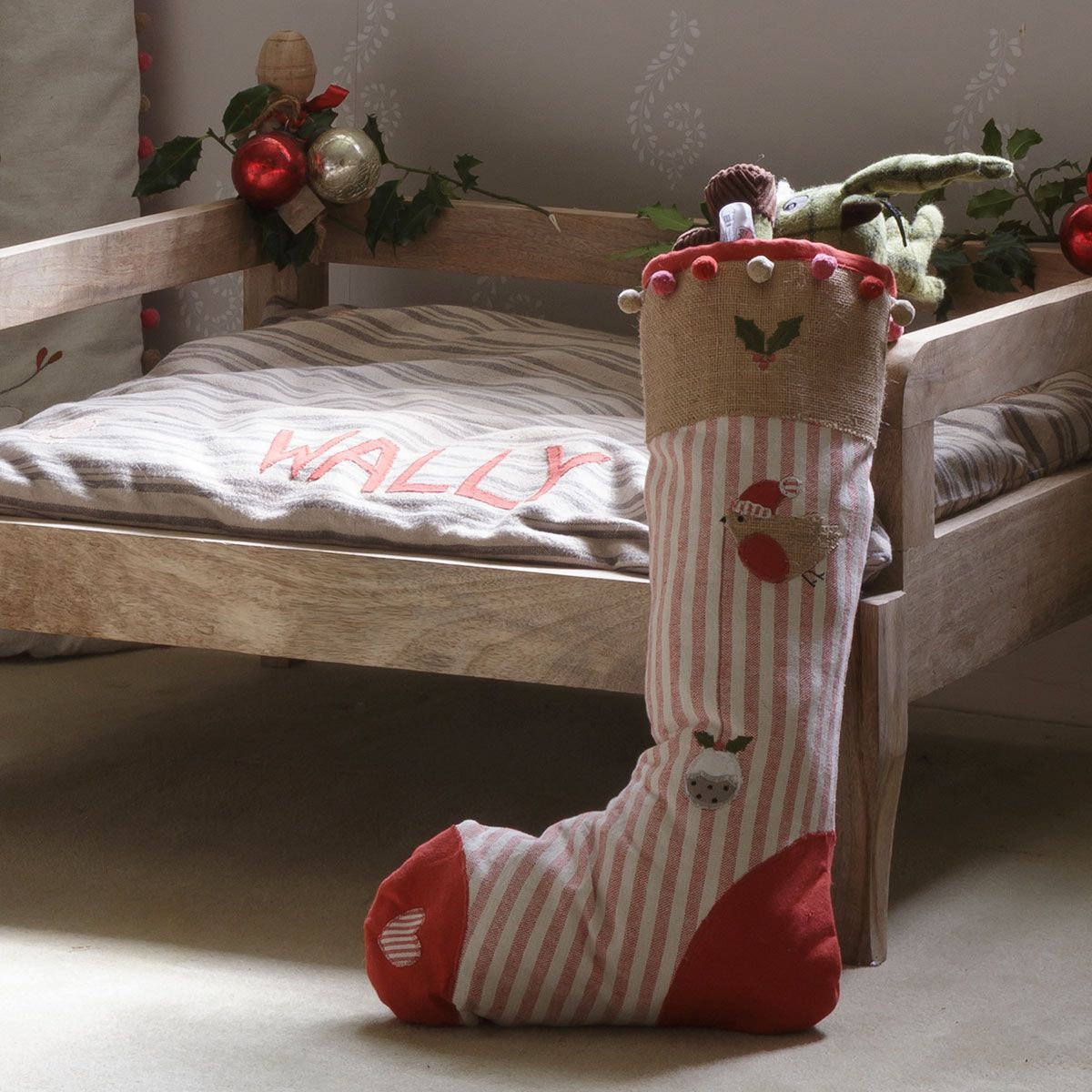 Christmas stocking at the foot of a child's wooden bed with foliage