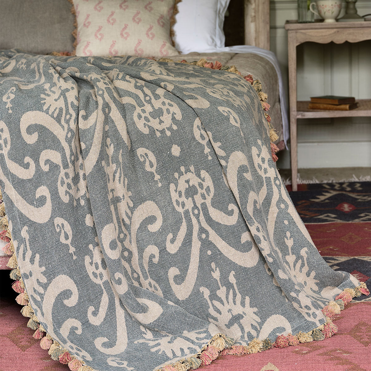 Summer Blue Sacha rustic linen throw draped over a bed with tassels