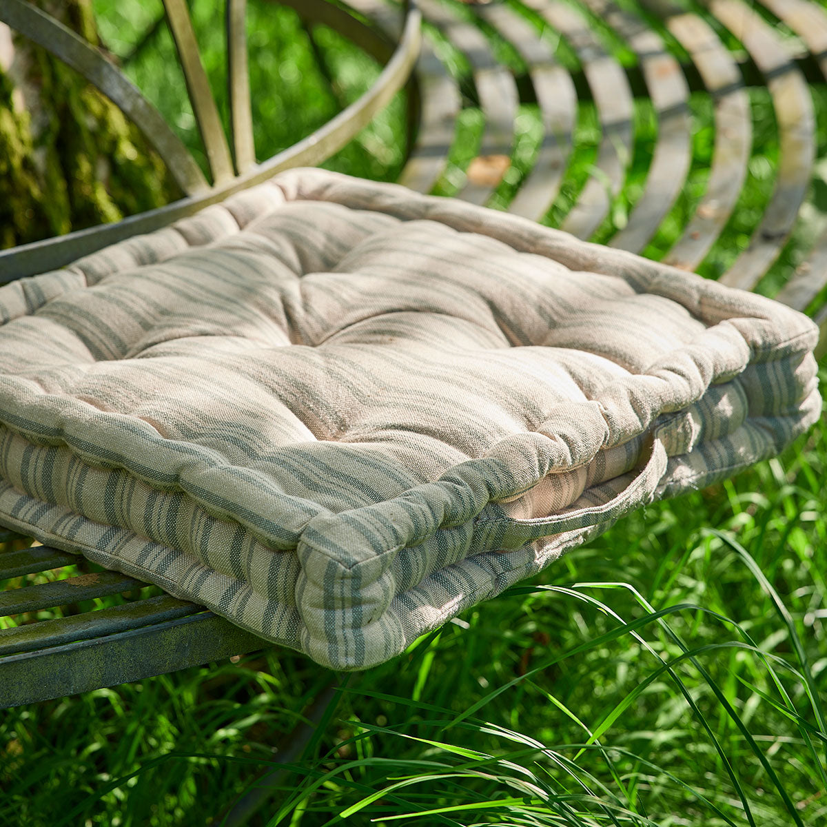 Beech sail blue ticking box cushion on a metal garden chair