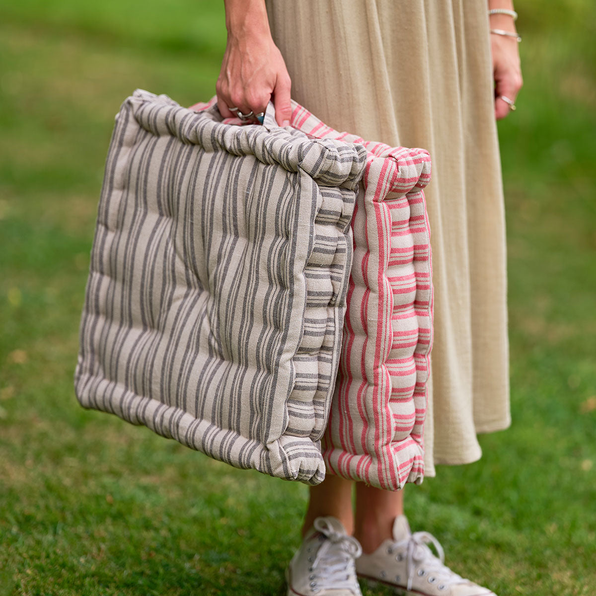 Woman carrying a ticking stripe box cushion by its carry handle