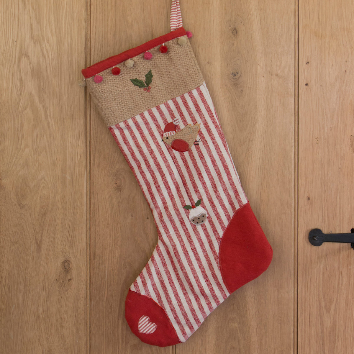 Robin and Pudding stocking in red ticking stripe hung on an oak door