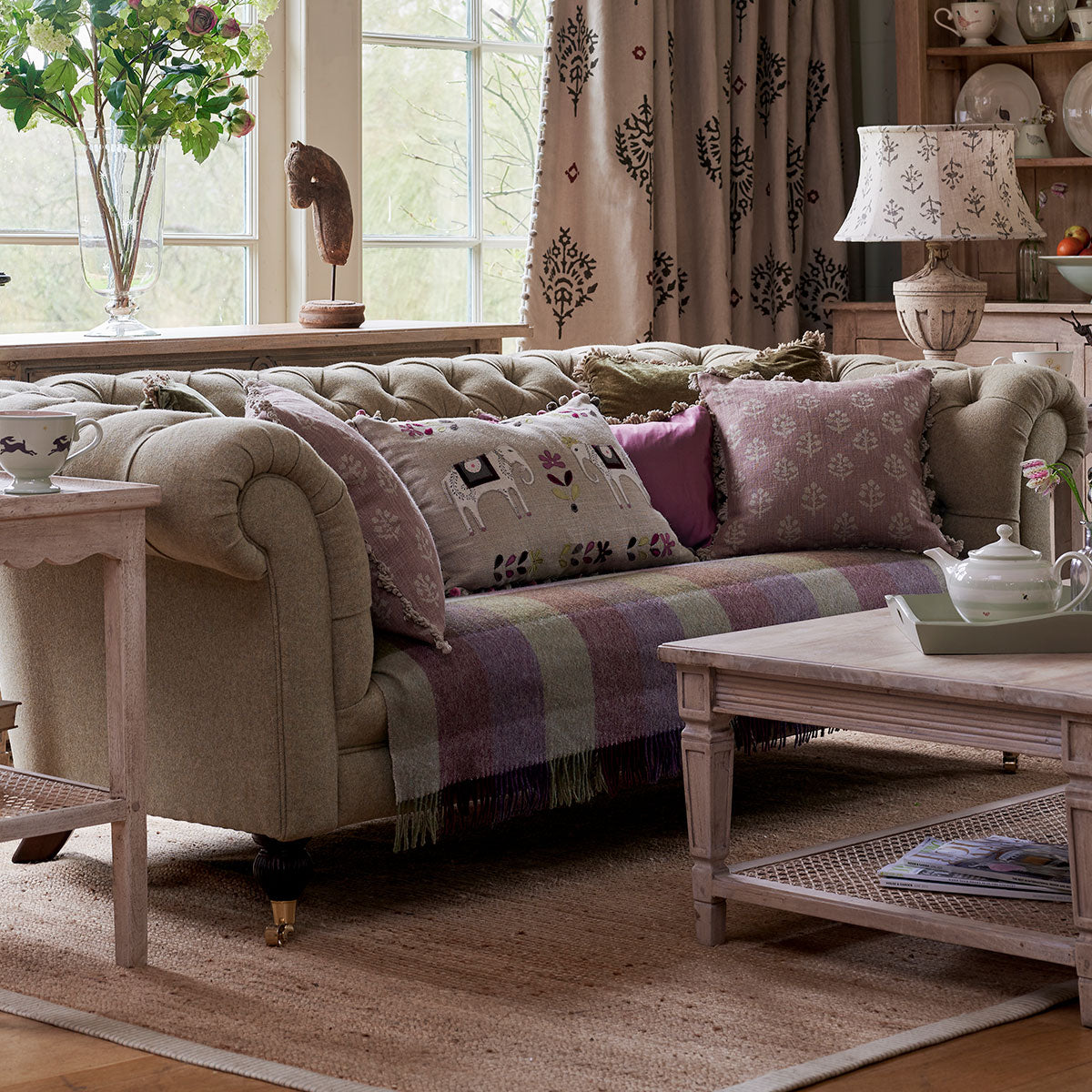 Harlequin lambswool throw across a chesterfield sofa with velvet cushions