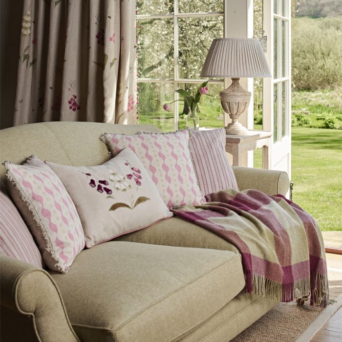 Ticking stripe cushions on a green sofa with a plum checked wool throw