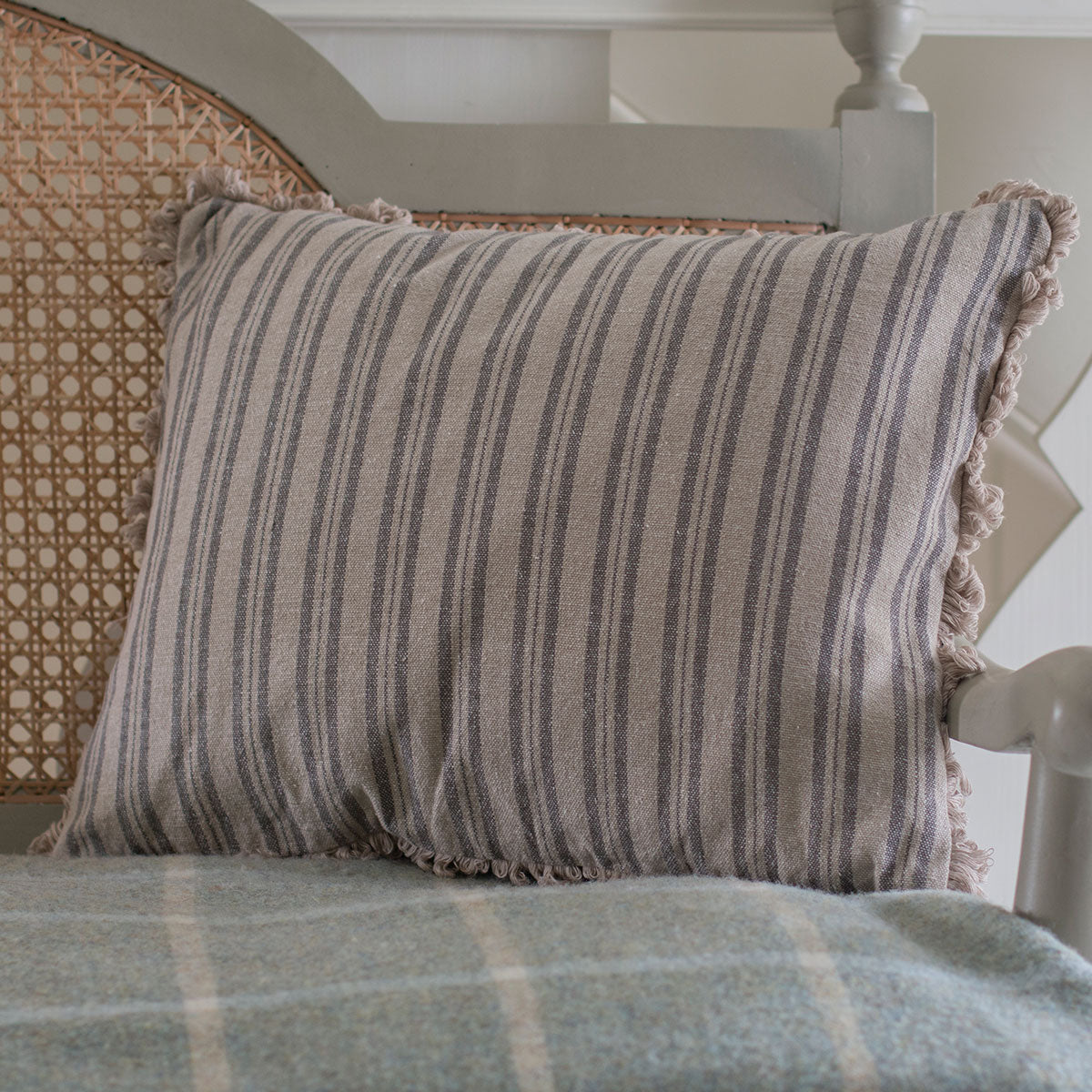 Charcoal ticking stripe cushion resting against a caned chair back