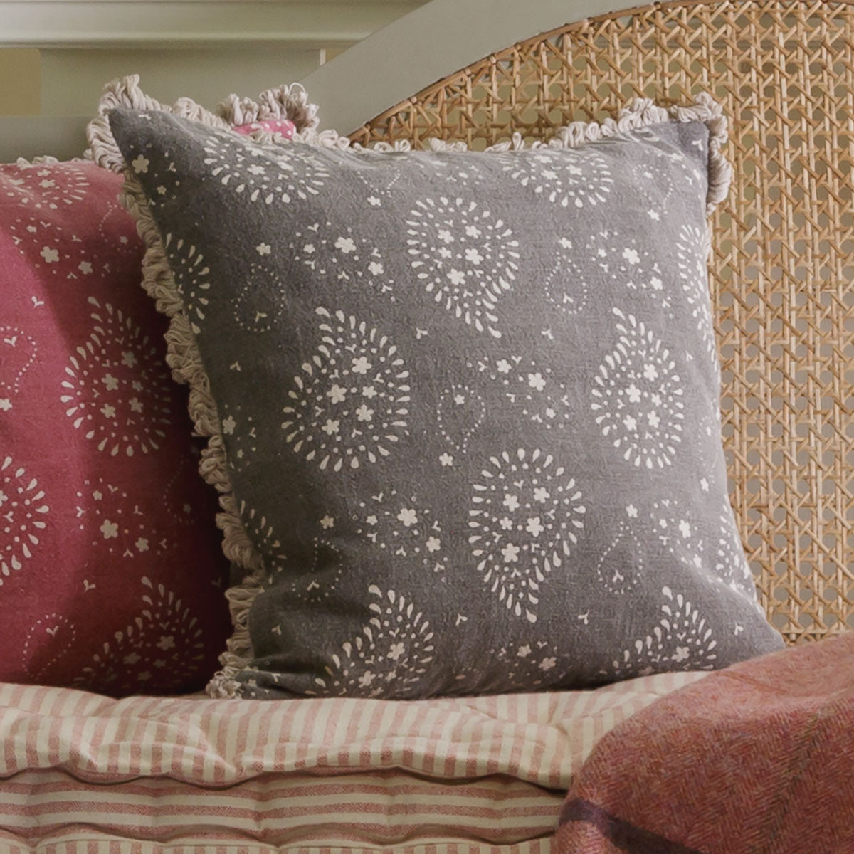 Charcoal Lullaby cushion in a basket chair with a rose linen cushion