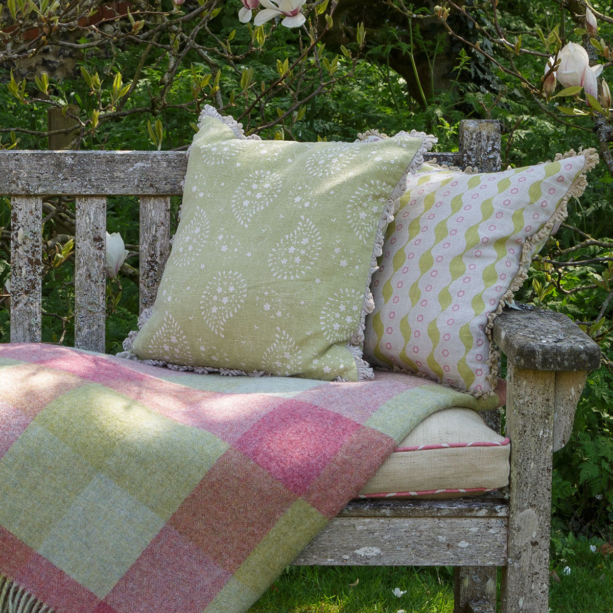 Summer Green Lullaby cushions on a garden bench with a check throw