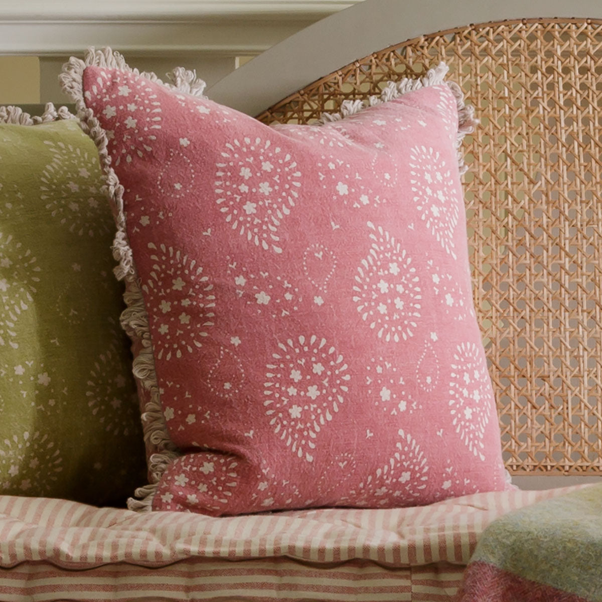 Rose Lullaby cushion on a sofa beside a green velvet cushion
