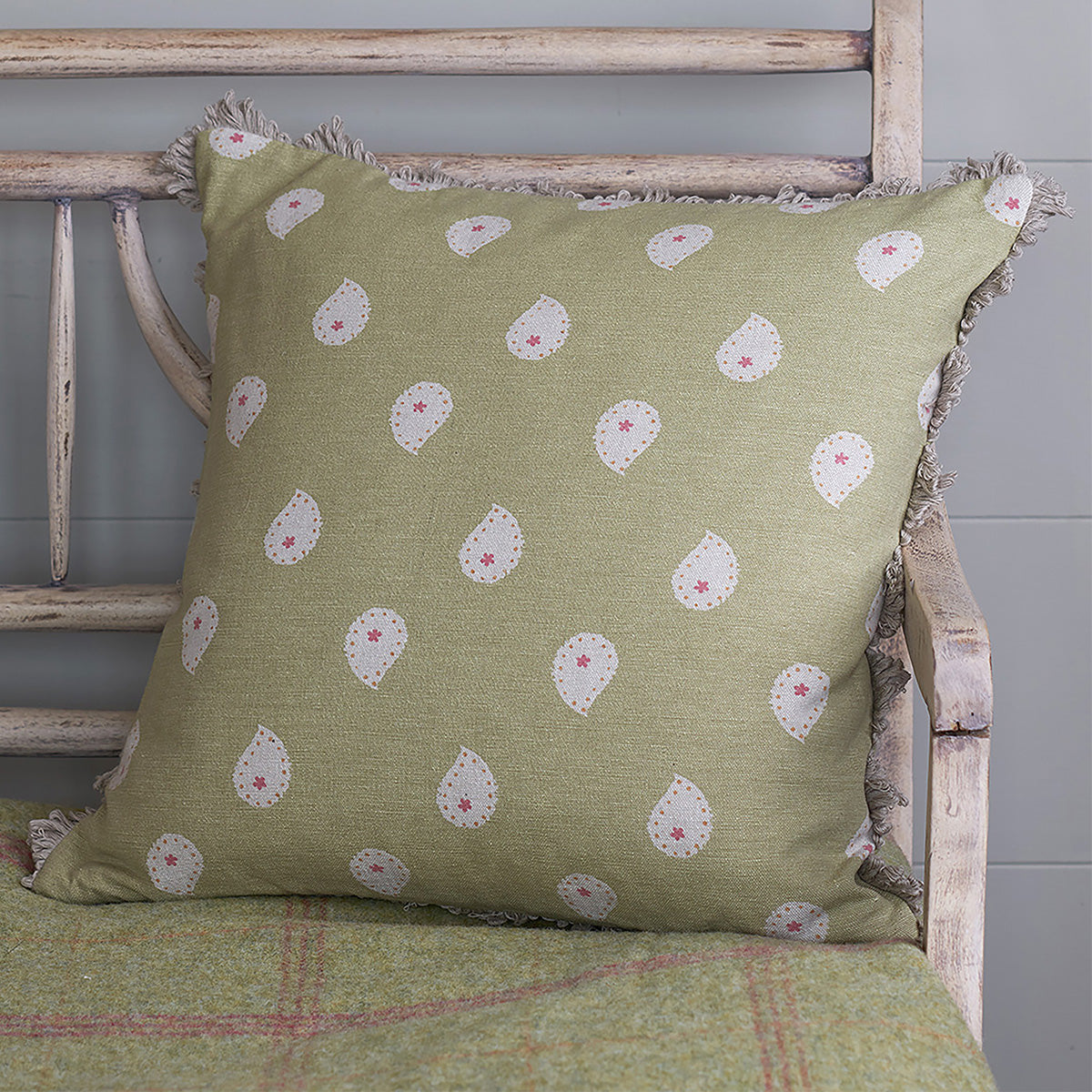 Summer Green Mika cushion resting on a wooden garden chair
