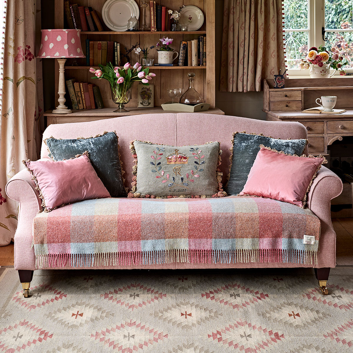 Deep sea blue velvet cushions on a pink checked sofa in a cottage sitting room