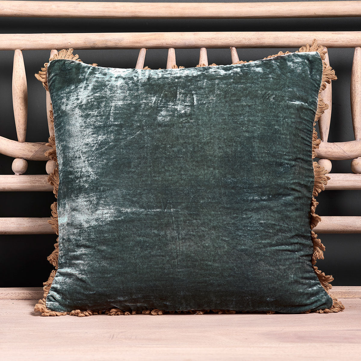 Deep sea blue velvet cushion with fan edge trim on a pale wooden bench