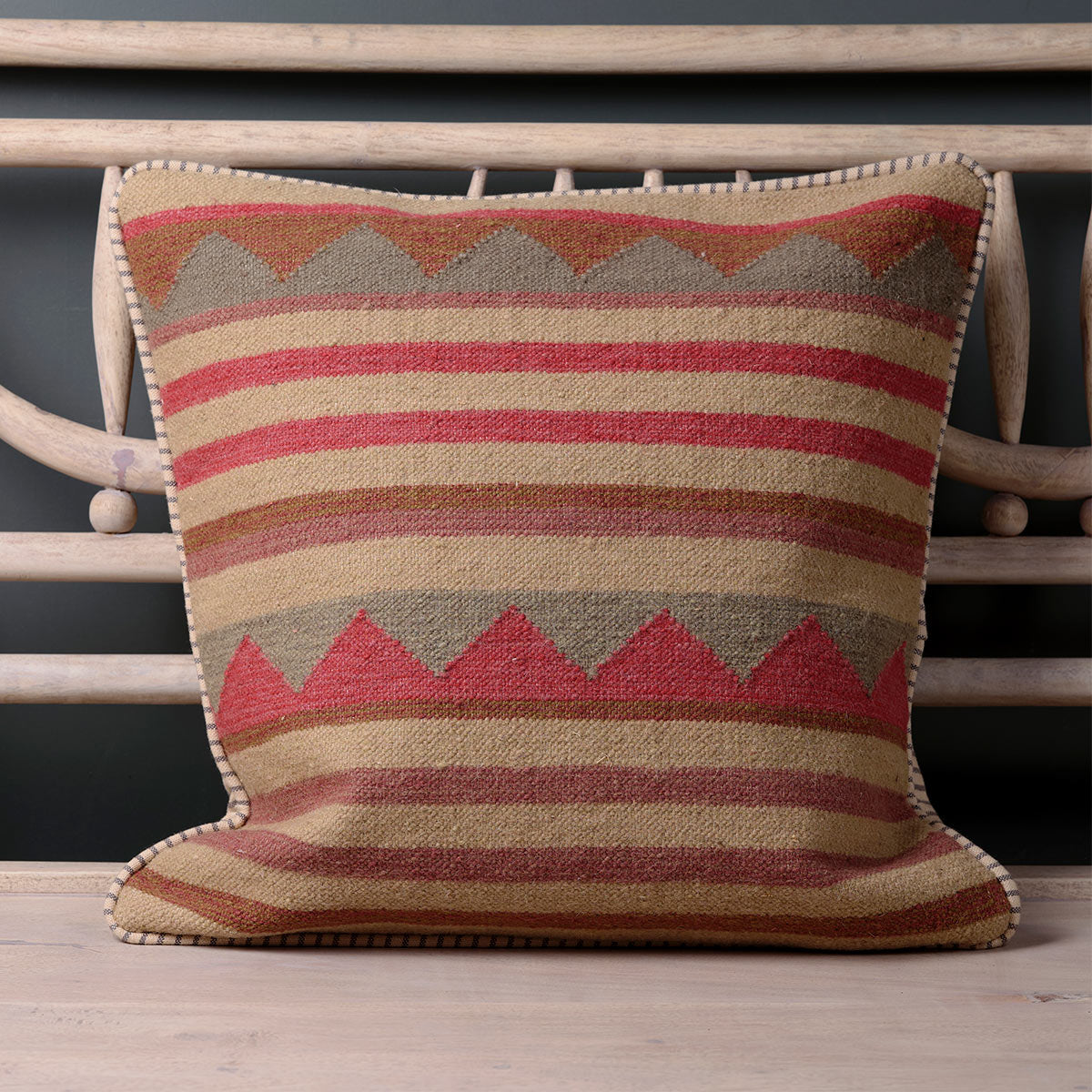 Handwoven kilim cushion with red and taupe zigzag bands on a bench