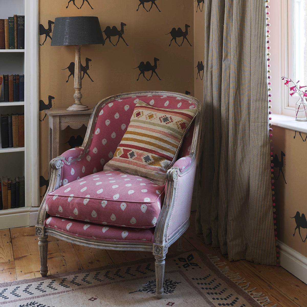 Library corner with camel-stencilled walls and kilim cushion on a pink chair