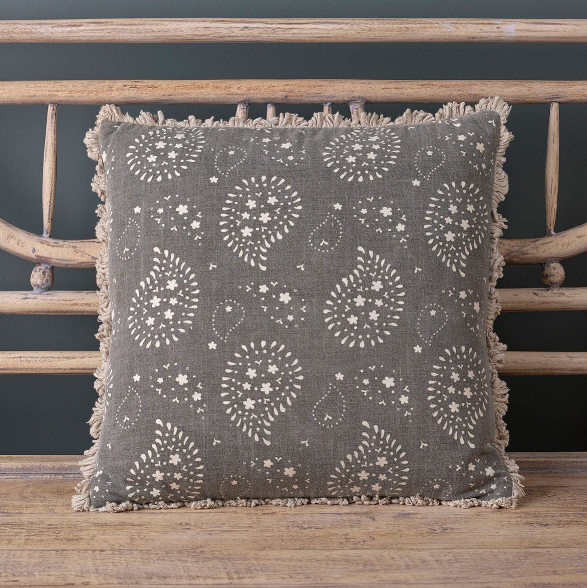 Charcoal Lullaby paisley cushion on a wooden bench against dark blue panelling