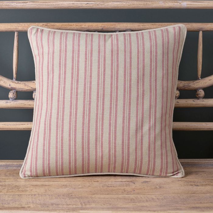 Dusky pink ticking stripe cushion with piped edge on a painted bench