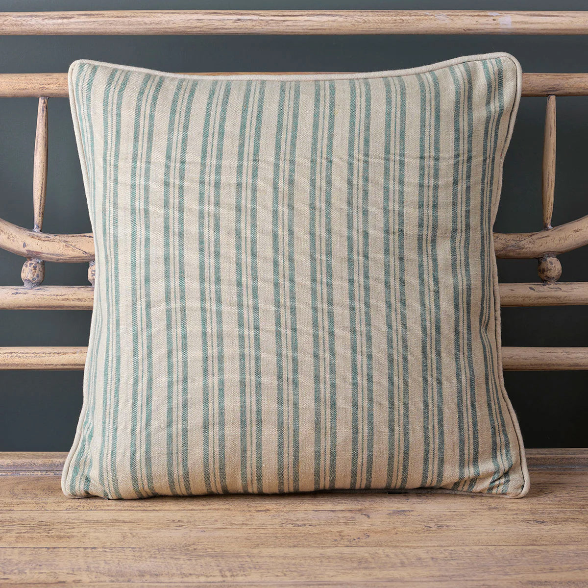 Summer blue ticking stripe cushion with piped trim on a wooden bench