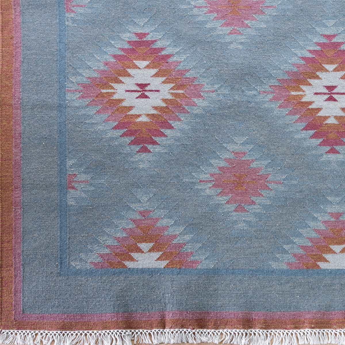 Corner of the Denim Shimla wool kilim, pink and rust diamonds with fringe