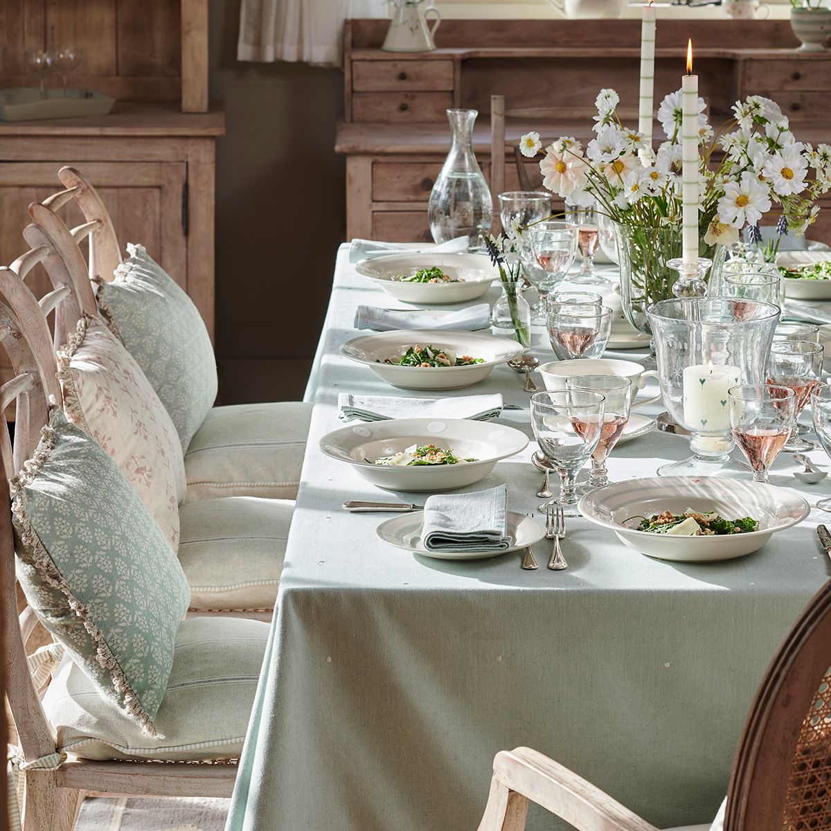 Duck egg spot tablecloth on a long dining table set with candles and daisies