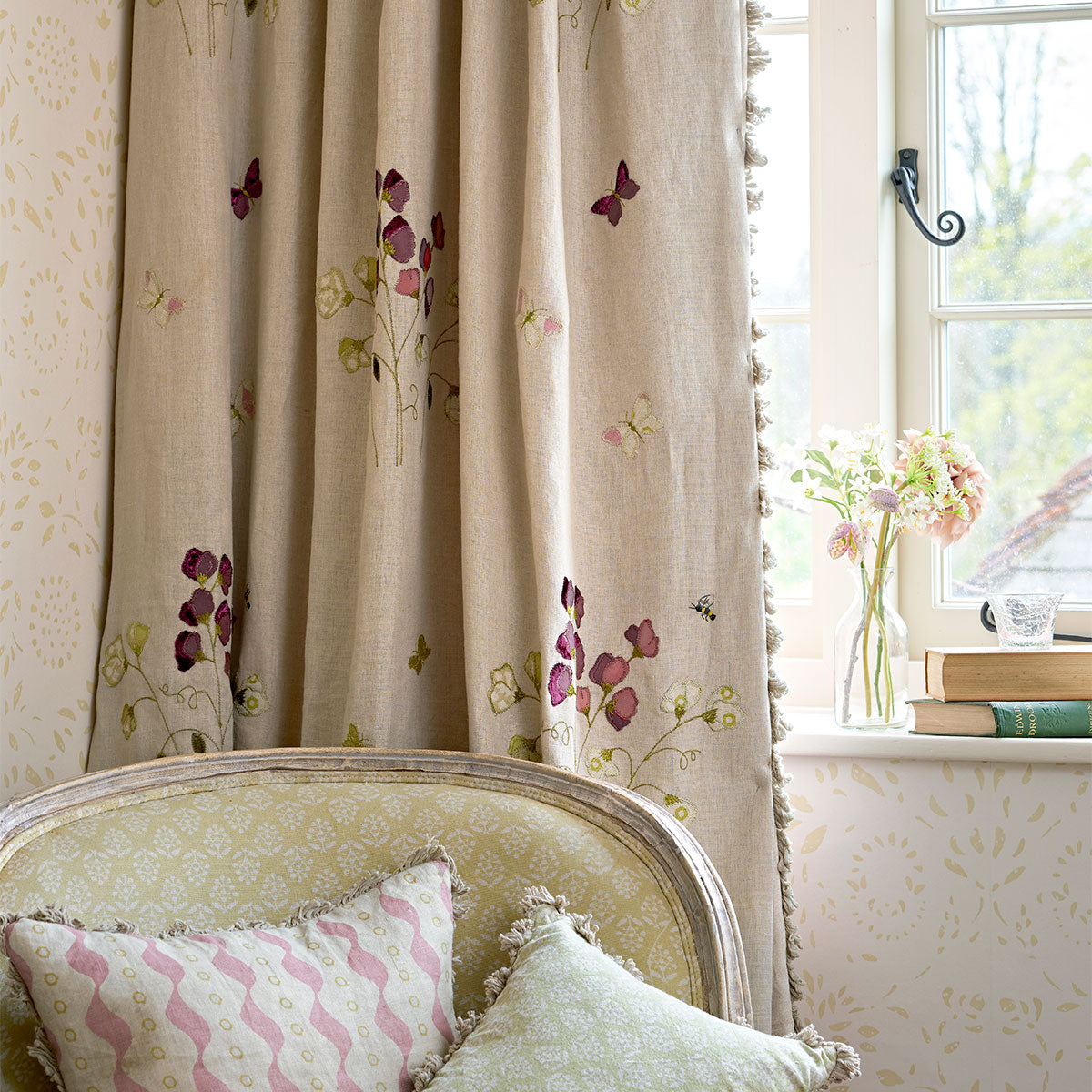 Sweet pea embroidered linen curtains at a window with pompom trim