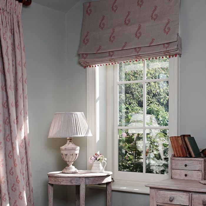 Bedroom window with red Shalini blind, curtains and a painted lamp table