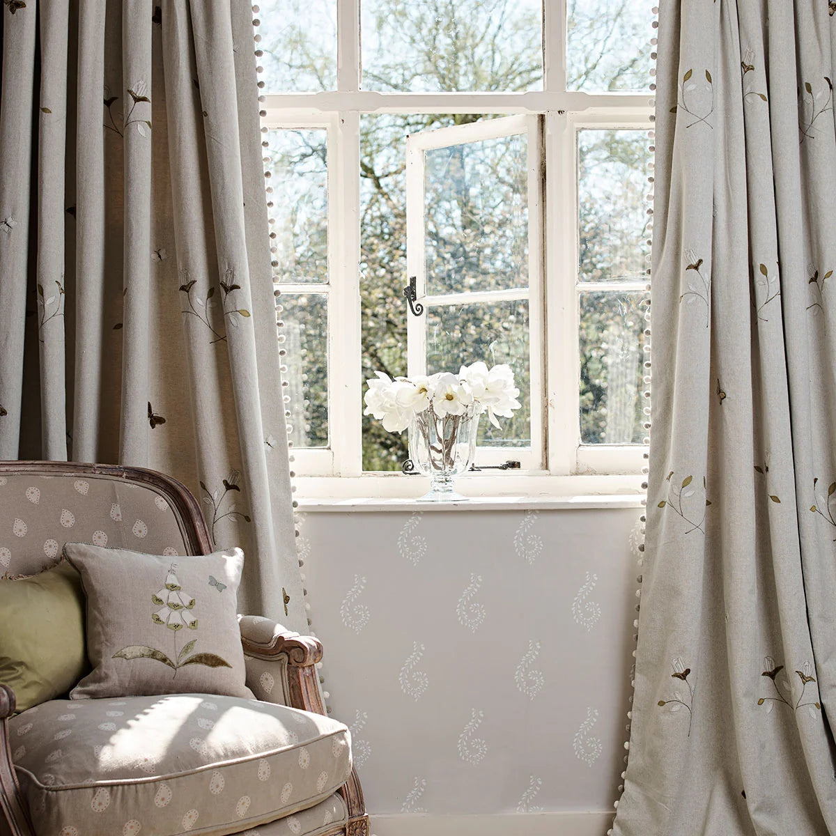 Grey Rosebud embroidered curtains at a window with a spotted armchair
