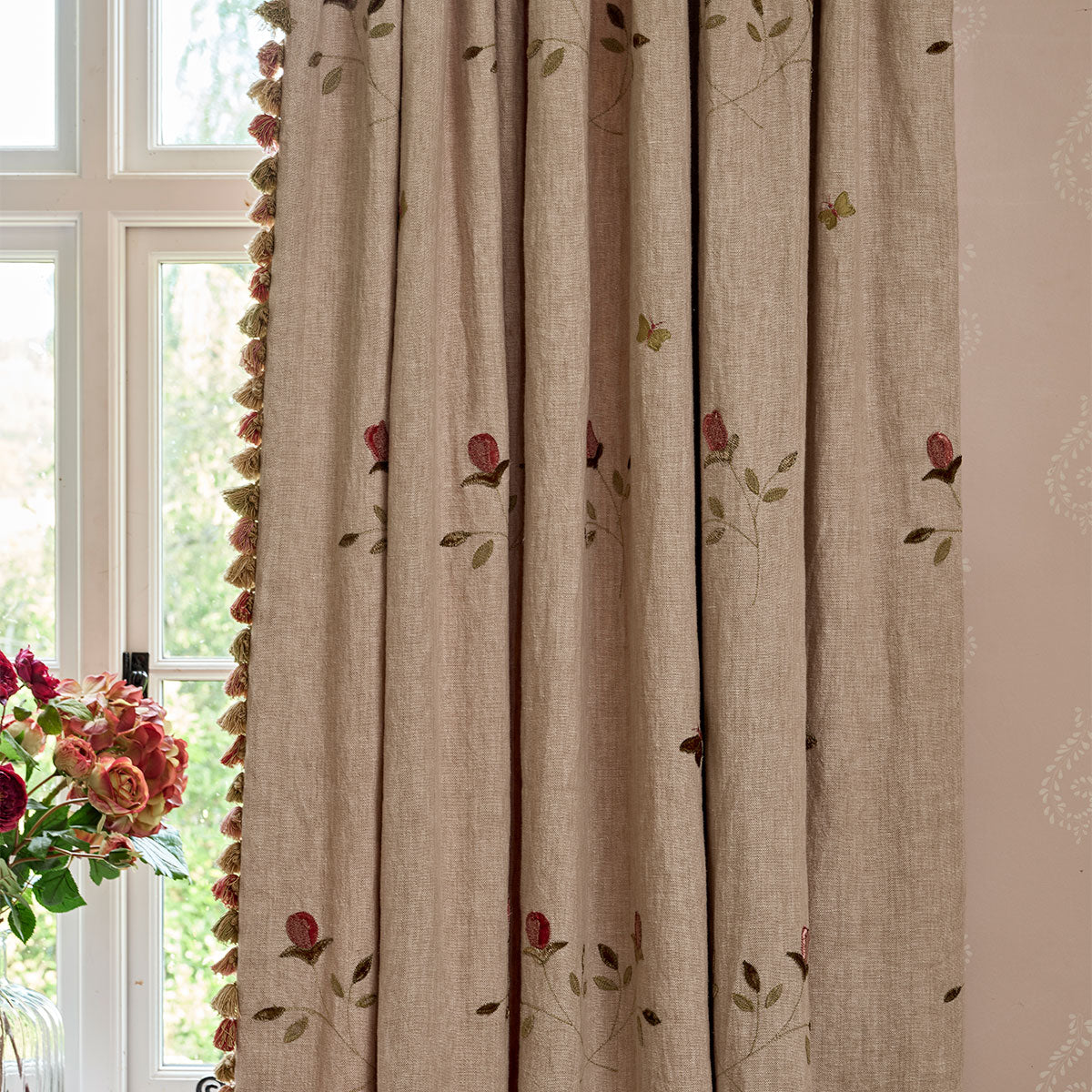 Curtain made in the rosebud embroidered linen hanging at a window