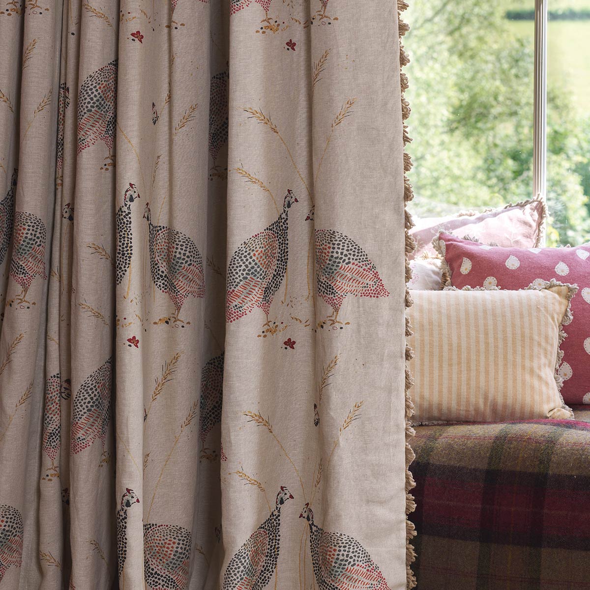 Guinea Fowl linen curtain hanging beside a cushioned window seat