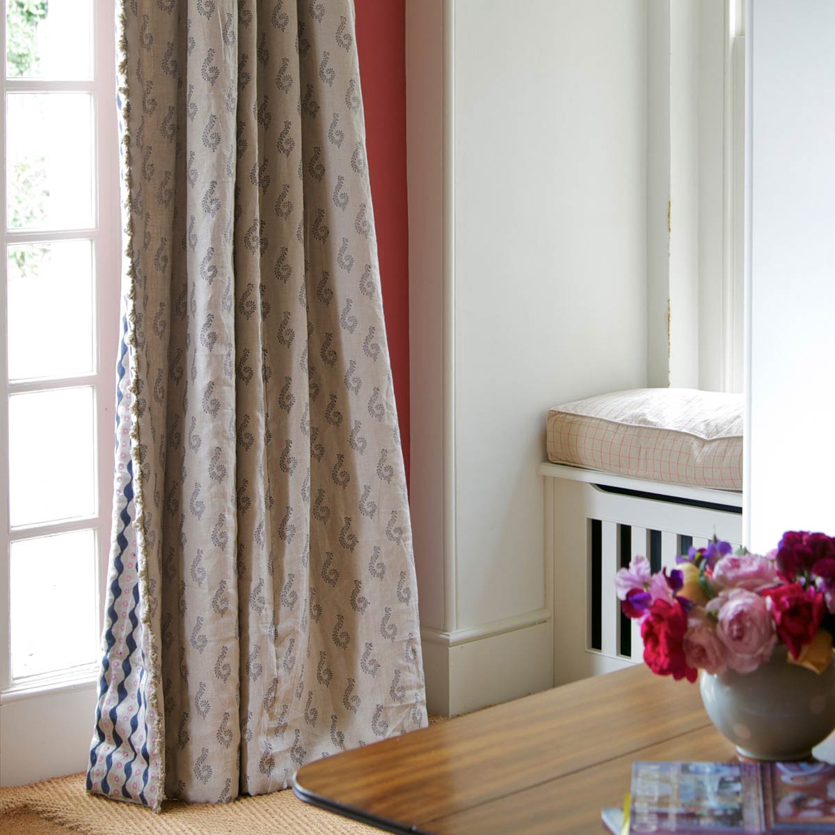 Graphite Shalini linen curtains hanging beside a window seat and red curtain