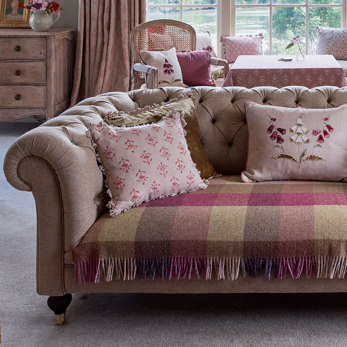Sofa in lichen tweed layered with pink cushions and a checked throw
