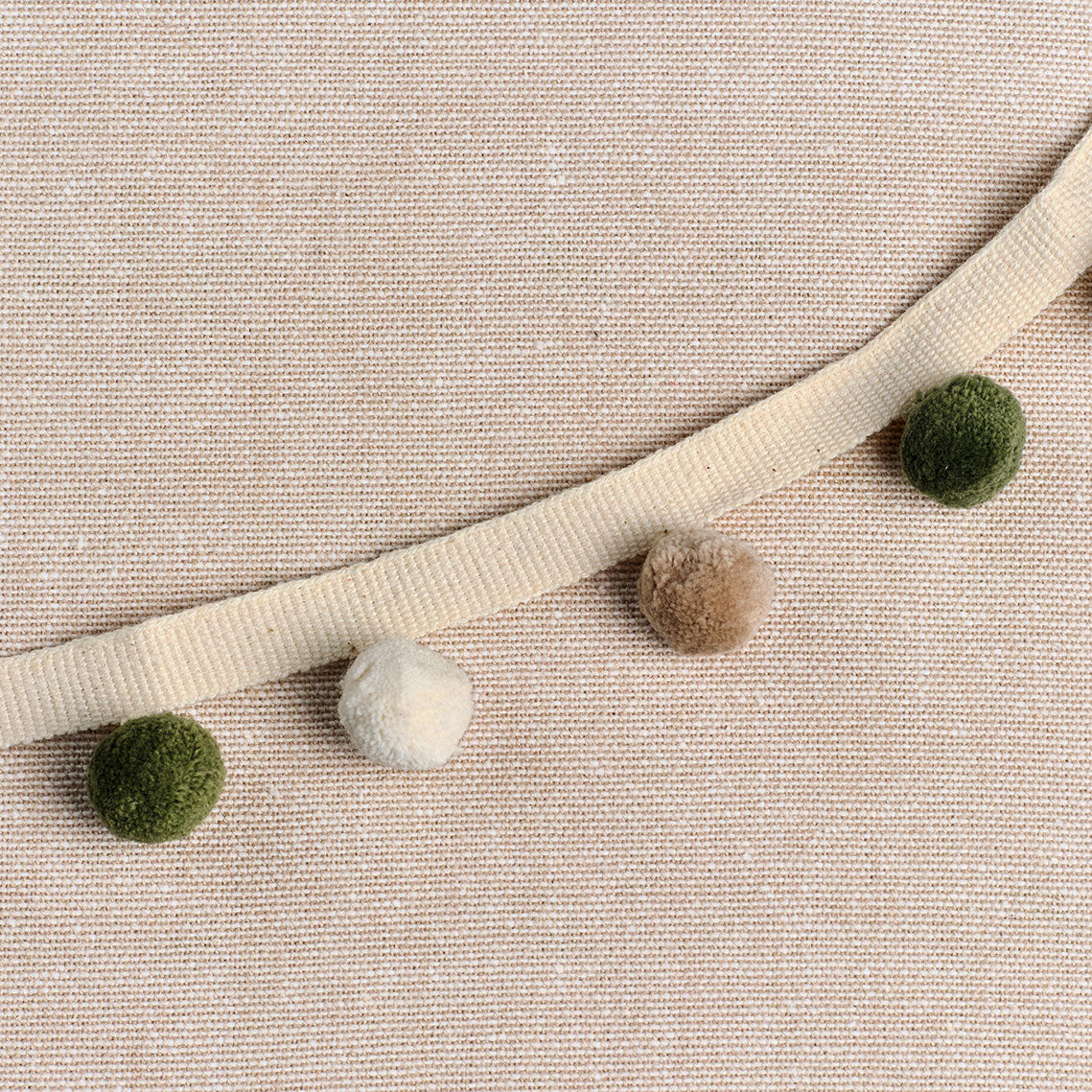 Dark green, light beech and ivory pom pom trim on linen