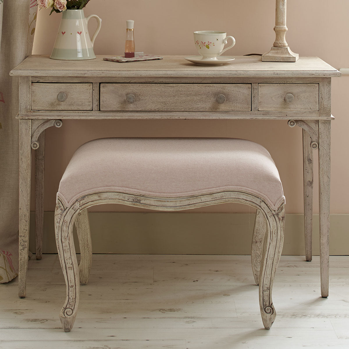 Small cabriole stool in pale pink linen at a painted dressing table
