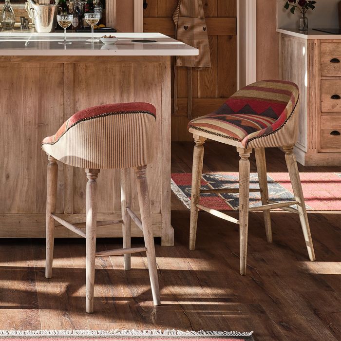 Two kilim-topped bar stools drawn up to a wooden kitchen island