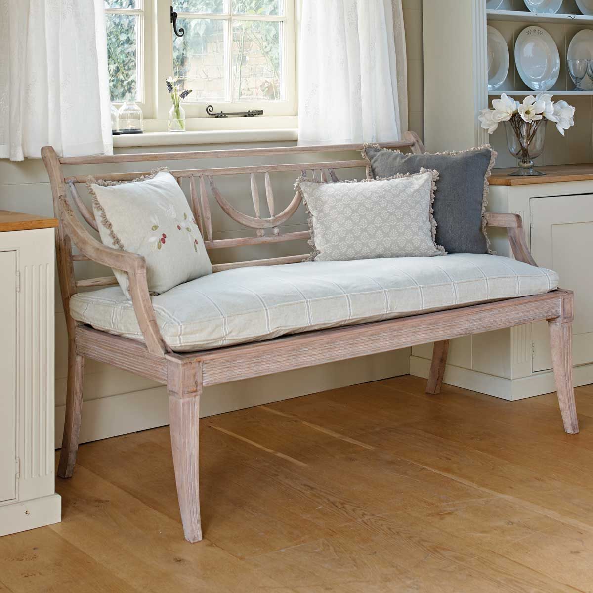 Gustavian bench with cushions beside a bright window in a hallway