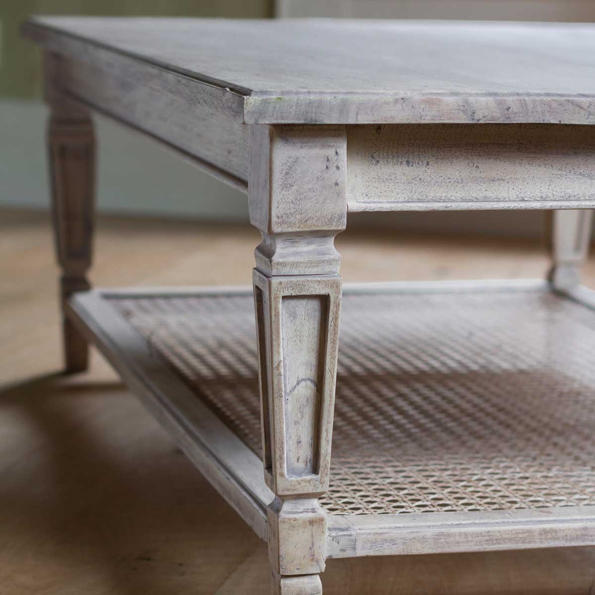 Close view of the turned leg and woven cane undershelf of the coffee table