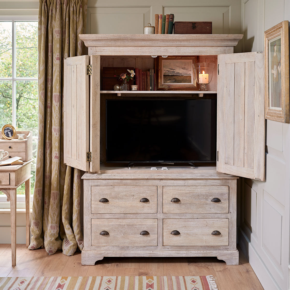 Small armoire opened to reveal a television above its four drawers