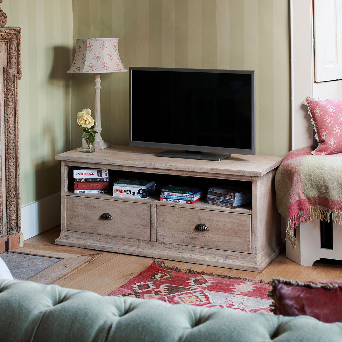 TV stand in a sitting room holding a television with media boxes on the shelf