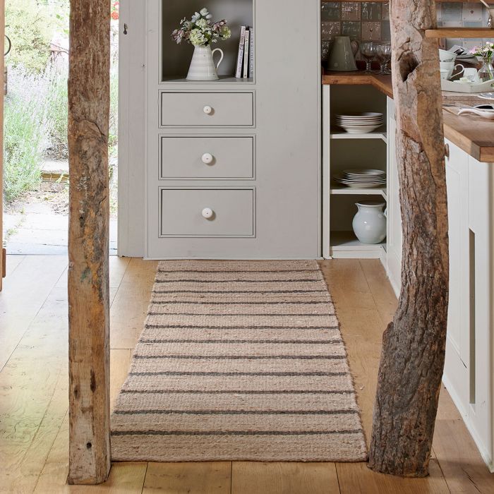Charcoal stripe hemp runner along a hallway beside a painted cupboard