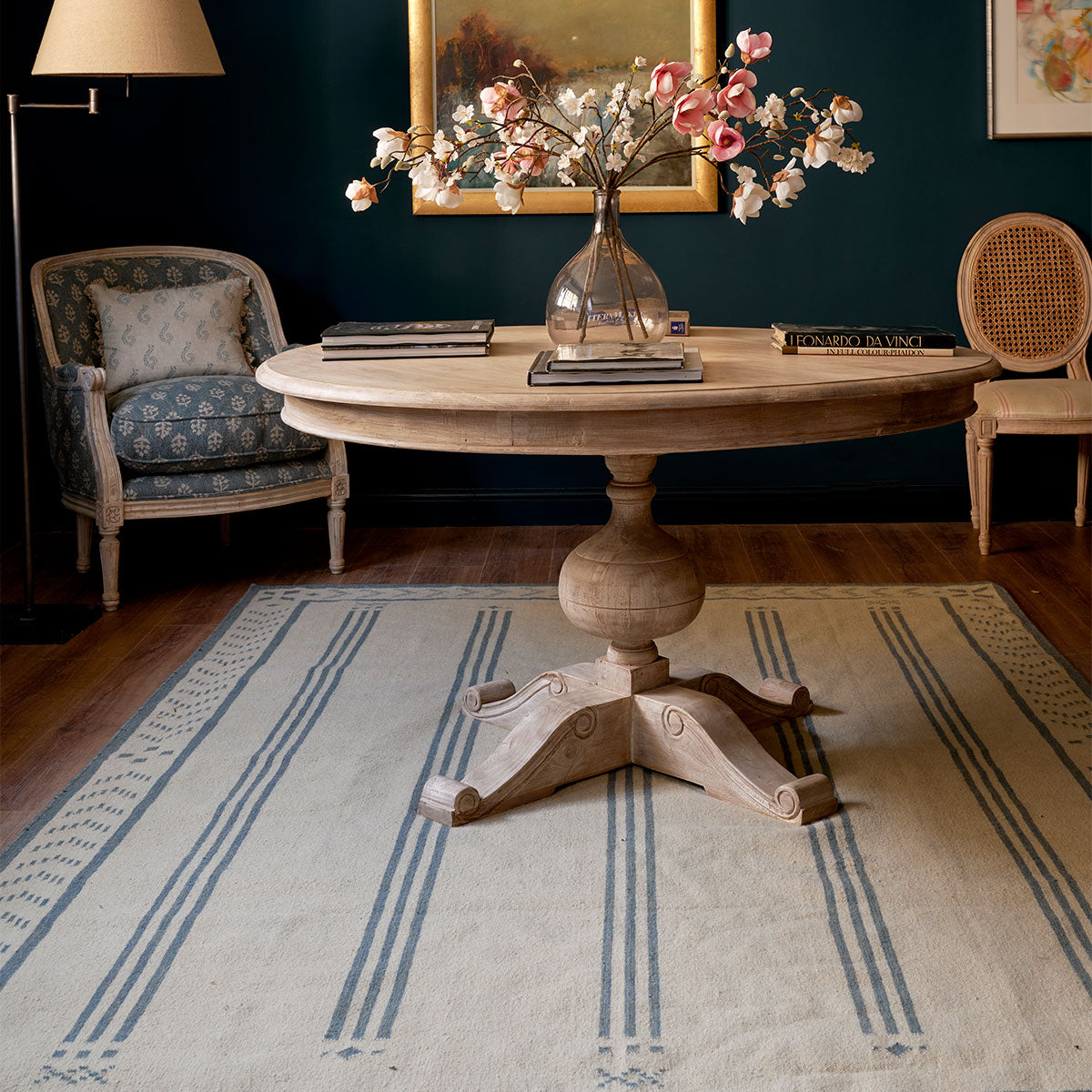 Blue Gustavian Stripe kilim beneath a pedestal table in a dark room