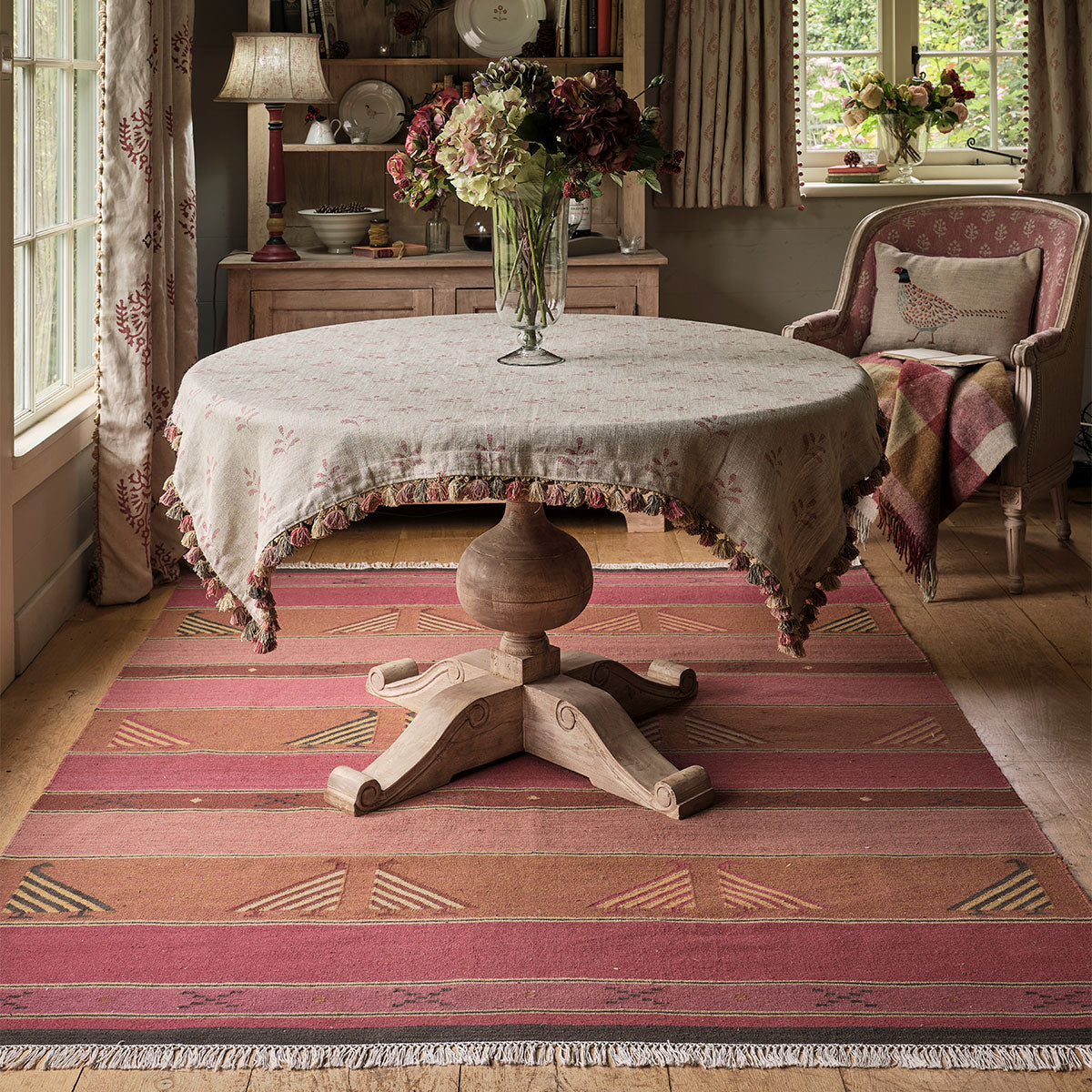 Round skirted table on the Indian Bird Rose kilim by a window
