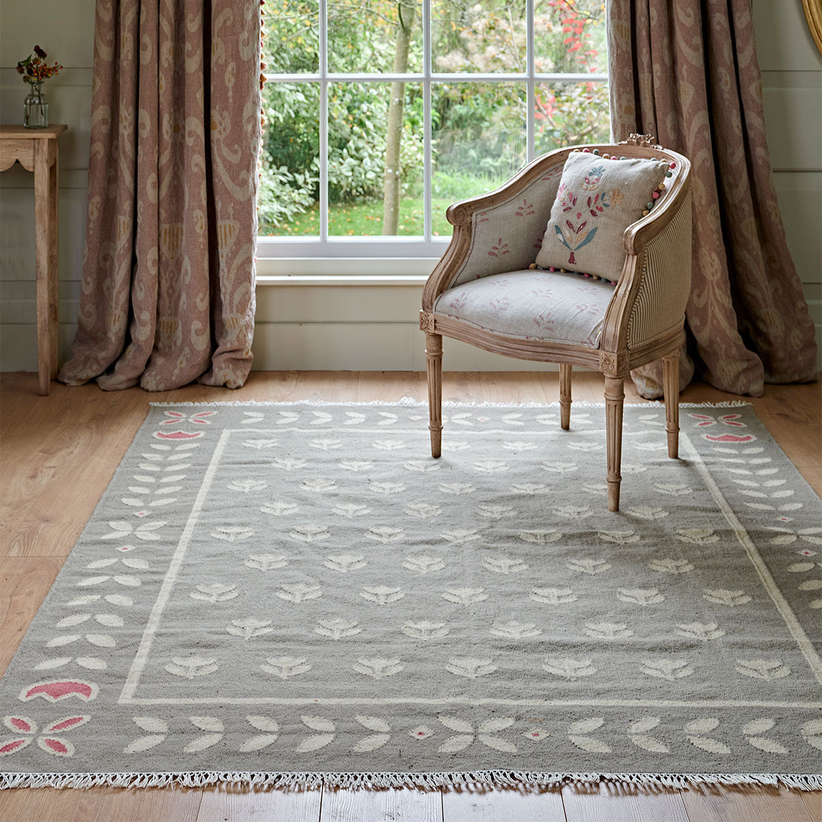 Smokey Blue Tulip kilim on the floor beside curtains and a Gustavian chair