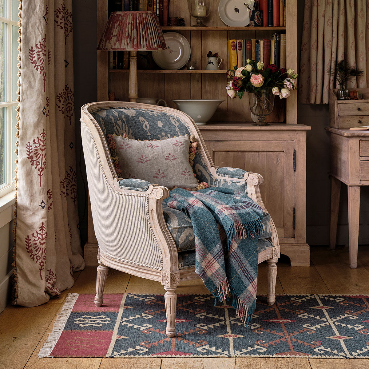Serrif kilim runner beneath a painted armchair with a checked wool throw