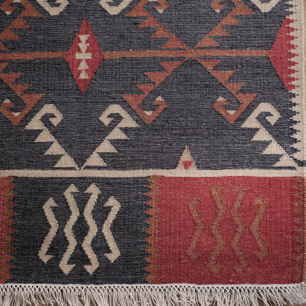 Close view of the Serrif kilim runner, rust and ivory motifs on dark blue
