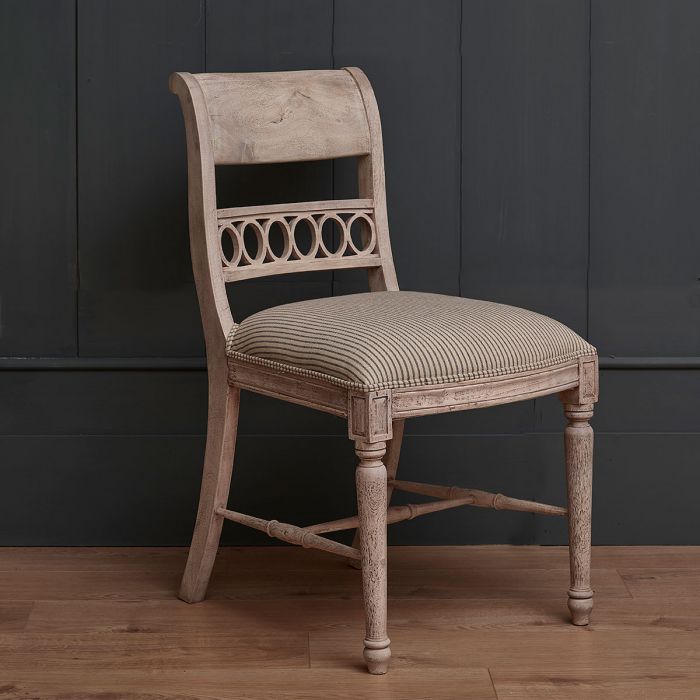Upholstered classic dining chair in ticking stripe against dark panelling