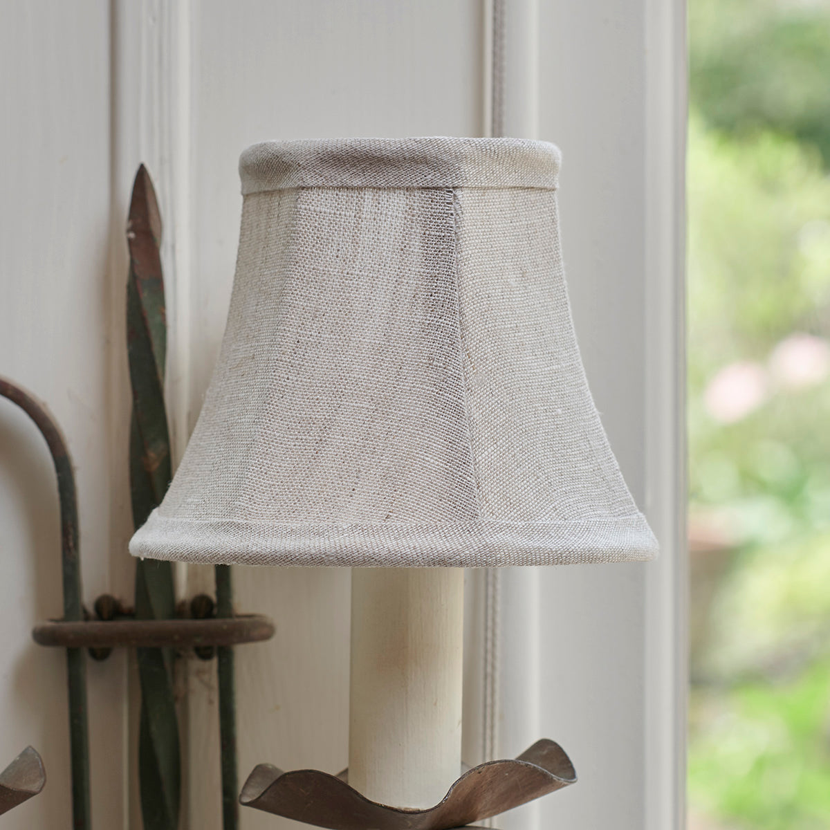 Natural linen framed lampshade unlit on a carved wall bracket
