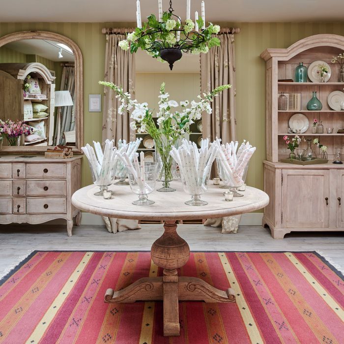 Jaisalmer striped kilim beneath a round pedestal table in a painted dining room