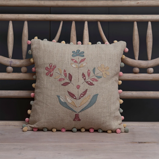 Indian Daisy linen cushion with pompom trim propped on a bench