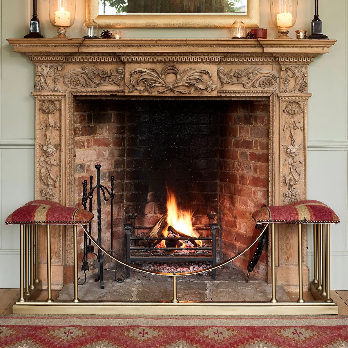Carved stone fireplace with fender and rusty rose velvet seat, fire lit