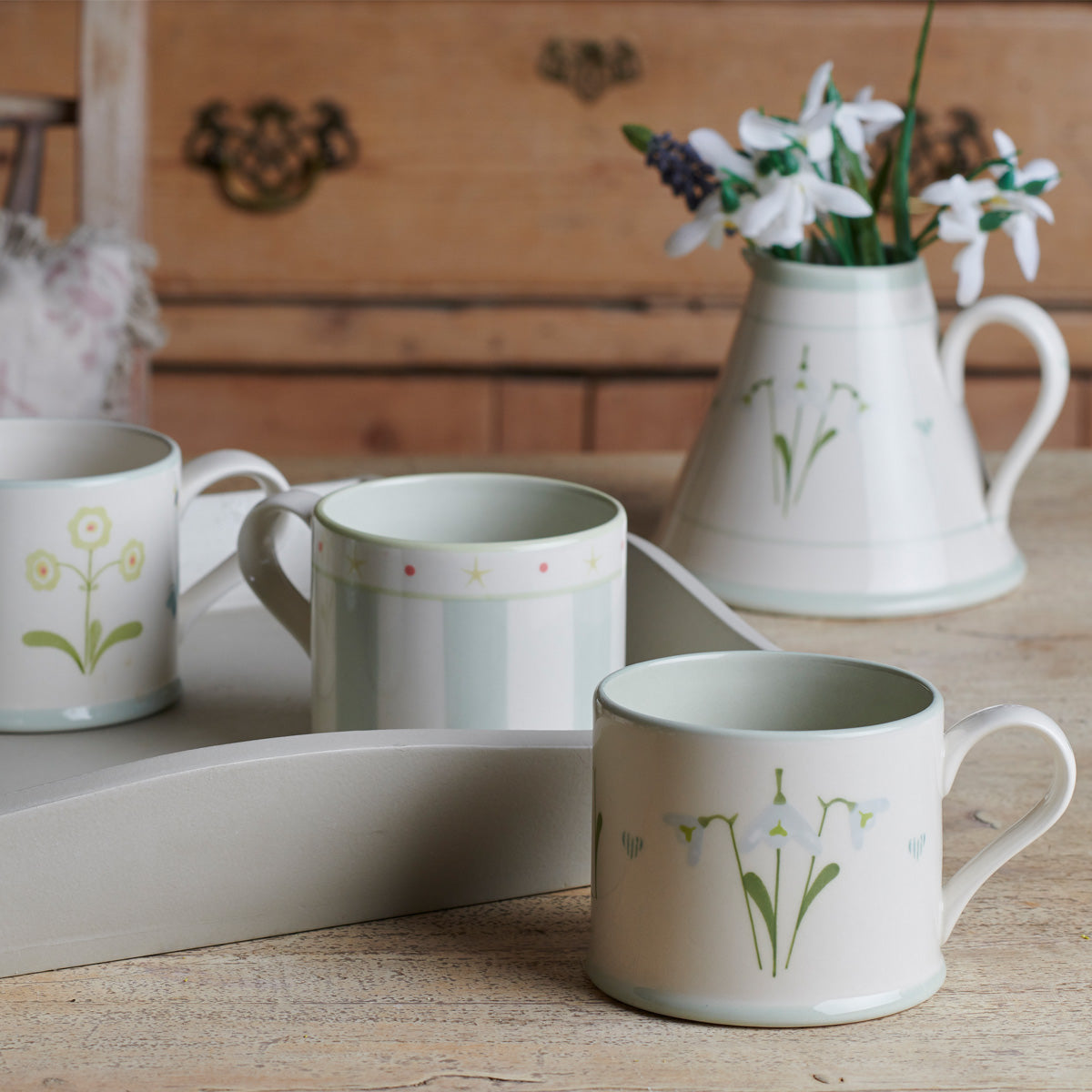 Snowdrop mugs and a jug of snowdrops arranged on a tray