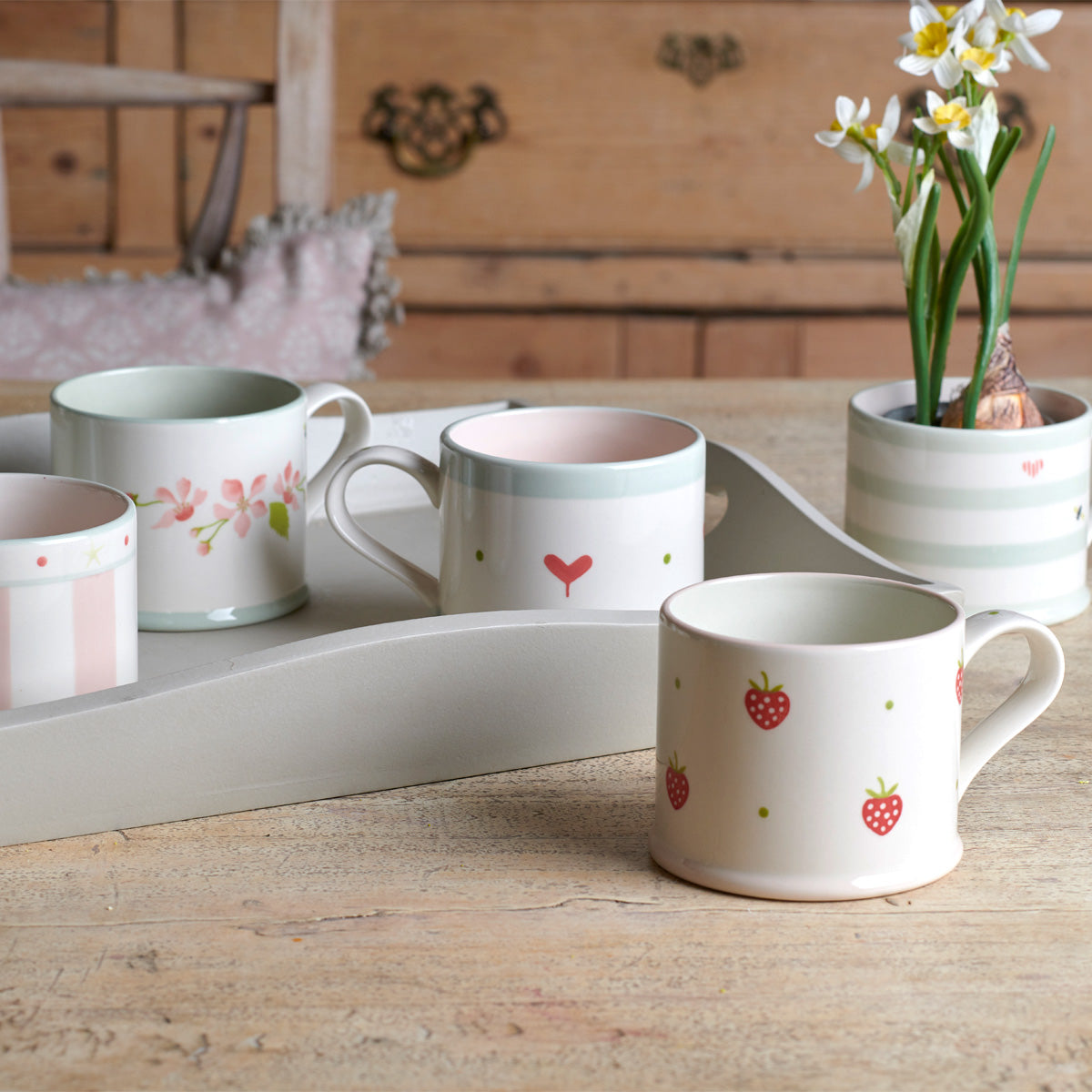 Group of Oscar mugs on a tray with daffodils behind