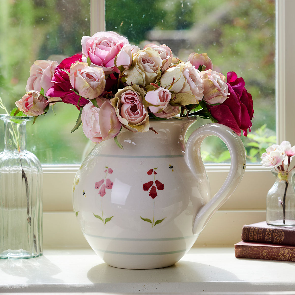 Foxgloves medium round jug filled with pink garden roses on a sill